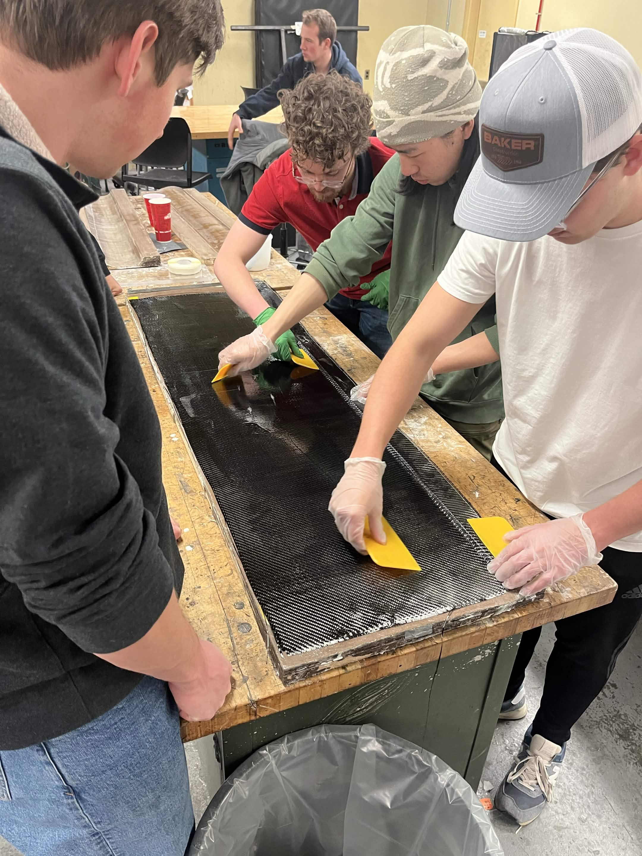 Nittany Motorsports team members applying carbon fiber to a chassis panel